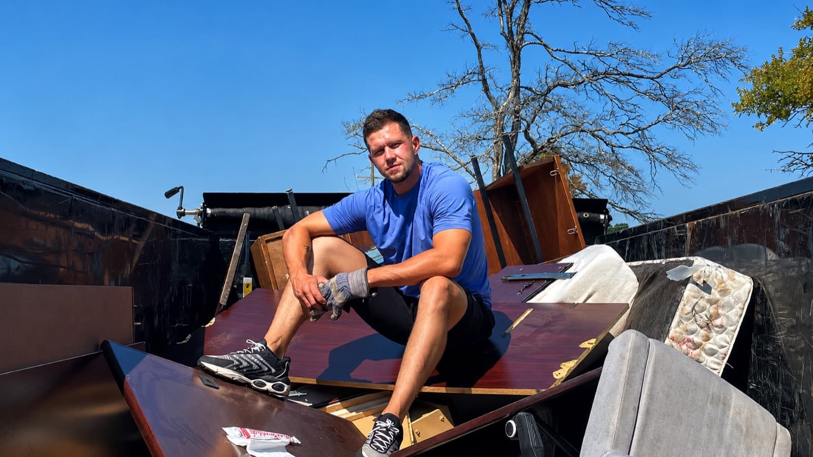 Kane Pro Junk Removal owner on a fully loaded dump trailer after a Northwest Arkansas cleanout